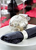 CHRISTMAS TABLE SETTING - NAPKIN AND SILVER BAUBLE ON A PLATE. SARAH EASTEL LOCATIONS/ DI ABLEWHITE