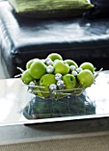 CHRISTMAS - METAL DISH WITH APPLES AND SILVER BAUBLES ON GLASS COFFEE TABLE IN LOUNGE. SARAH EASTEL LOCATIONS/ DI ABLEWHITE