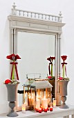 CHRISTMAS - TABLE ON LANDING WITH URNS  RED AMARYLLIS AND RED BAUBLES  MIRROR  STORM LANTERN  CANDLES.  SARAH EASTEL LOCATIONS/ DI ABLEWHITE