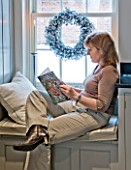 CHRISTMAS - DI ABLEWHITE READING IN THE WINDOW SEAT IN THE KITCHEN. SARAH EASTEL LOCATIONS/ DI ABLEWHITE