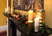 CLARE MATTHEWS CHRISTMAS HOUSE INTERIOR: THE DINING ROOM - CANDLES  BAUBLES  HOLLY AND TAPESTRY ABOVE THE FIREPLACE