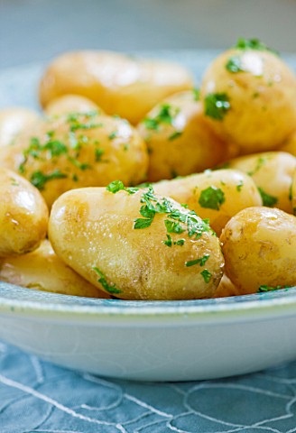 DESIGNER_CLARE_MATTHEWS__CLOSE_UP_OF_COOKED_POTATOES_WITH_BUTTER_AND_PARSLEY__IN_A_BLUE_BOWL_EDIBLE_