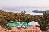 DESIGNER GINA PRICE - CORFU - VILLA ONEIRO -  VIEW FROM BEDROOM BALCONY TO THE INFINITY POOL WITH MOROCCAN SUN LOUNGERS AND SEA AND ALBANIAN MOUNTAINS BEYOND