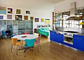 ROSE GRAY AND SCULPTOR DAVID MACILWAINE: DAVIDS ART STUDIO WITH COLOURED CHAIRS  BLUE KITCHEN UNITS  AND CANVASES ON WALLS