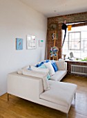 ROSE GRAY AND SCULPTOR DAVID MACILWAINE: DAVIDS ART STUDIO WITH CANVASES ON WALL BESIDE SOFA WITH BLUE  GREEN AND WHITE CUSHIONS  EASEL AND MOBILE