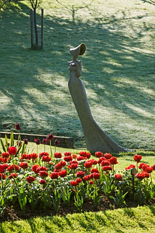 PASHLEY_MANOR_GARDEN__EAST_SUSSEX__SPRING__EARLY_MORNING_LIGHT_ON_TREES_WITH_A_SCULPTURE_MAY_BY_ANN_