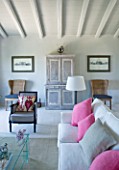 DESIGNER: CLAIRE SKINNER  ROU ESTATE  CORFU: HOUSE INTERIOR - LIVING ROOM IN GREY  CREAM AND PINK. GLASS COFFEE TABLE  SOFA WITH CUSHIONS.