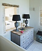 DESIGNER: CLAIRE SKINNER  ROU ESTATE  CORFU: HOUSE INTERIOR - LIVING ROOM IN GREY  CREAM AND PINK. WOODEN GREY CABINET WITH LAMPS AND VIEW THROUGH TO KITCHEN
