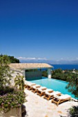 PRIVATE VILLA  CORFU  GREECE. DESIGN BY ALITHEA JOHNS - DECKCHAIRS BESIDE THE SWIMMING POOL WITH VIEW OF ALBANIA BEYOND