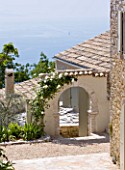 THE ROU ESTATE  CORFU: STONE ARCH COVERED WITH ICEBERG ROSE AND VIEW TO SEA BEYOND