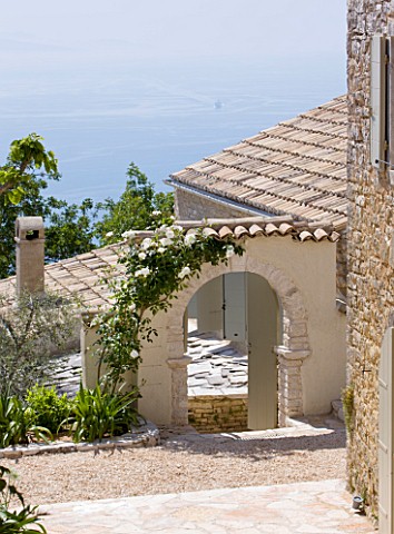 THE_ROU_ESTATE__CORFU_STONE_ARCH_COVERED_WITH_ICEBERG_ROSE_AND_VIEW_TO_SEA_BEYOND