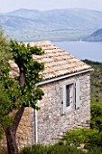 THE ROU ESTATE  CORFU: STONE BUILDING WITH ALBANIAN MOUNTAINS IN THE BACKGROUND