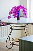 PAULA PRYKES HOUSE  SUFFOLK: PINK ORCHID FLOWERS IN VASE ON METAL AND GLASS TABLE