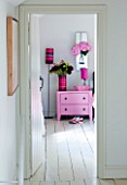 PAULA PRYKES HOUSE  SUFFOLK: VIEW INTO BEDROOM WITH PINK BEDSIDE TABLE AND FLOWERS