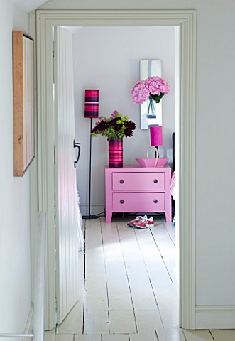 PAULA_PRYKES_HOUSE__SUFFOLK_VIEW_INTO_BEDROOM_WITH_PINK_BEDSIDE_TABLE_AND_FLOWERS