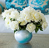 PAULA PRYKES HOUSE  SUFFOLK: VASE OF WHITE PEONIES ON COFFEE TABLE IN THE GARDEN ROOM