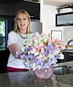 PAULA PRYKES HOUSE  SUFFOLK: PAULA ARRANGING A VASE OF SWEET PEAS IN HER KITCHEN