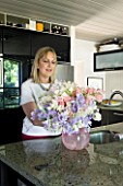 PAULA PRYKES HOUSE  SUFFOLK: PAULA ARRANGING A VASE OF SWEET PEAS IN HER KITCHEN