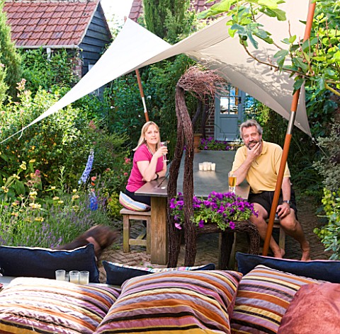 PAULA_PRYKES_HOUSE__SUFFOLK_PAULA_AND_HER_HUSBAND_RELAX_AT_THE_TABLE_IN_THEIR_COURTYARD_GARDEN