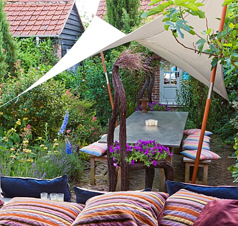 PAULA_PRYKES_HOUSE__SUFFOLK_VIEW_OUT_TO_COURTYARD_GARDEN_WITH_CANVAS_SAILCANOPY_OVER_SEATING_AREA