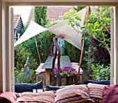 PAULA PRYKES HOUSE  SUFFOLK: VIEW OUT TO COURTYARD GARDEN WITH CANVAS SAIL/CANOPY OVER SEATING AREA