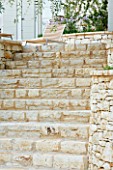 CORFU  GREECE: DESIGNER: DOMINIC SKINNER - MEDITTERANEAN STYLE GARDEN  - STONE STEPS LEADING UP TO PATIO WITH SUNLOUNGER