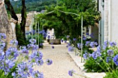 THE ROU ESTATE  CORFU  GREECE: DESIGNER: DOMINIC SKINNER - MEDITTERANEAN STYLE GARDEN - GRAVEL PATH AND AGAPANTHUS WITH WELL