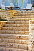 CORFU  GREECE: DESIGNER: DOMINIC SKINNER - STONE STEPS UP TO PATIO WITH SUN LOUNGERS