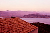 THE ROU ESTATE  CORFU  GREECE: DESIGNER: DOMINIC SKINNER - VIEW OVER HOUSE ROOF TO ALBANIAN MOUNTAINS AT DAWN