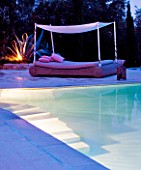 THE ROU ESTATE  CORFU  GREECE: DESIGNER: DOMINIC SKINNER -  A PLACE TO SIT - THE SWIMMING POOL AREA  LIT UP AT NIGHT WITH LUXURY BED AND CACTUS. LIGHTING