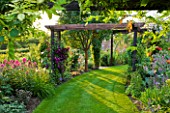 MEADOW FARM  WORCESTERSHIRE: CURVED LAWN AND PERGOLA IN SUMMER