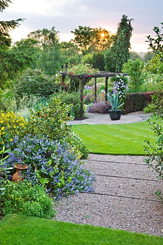 MEADOW_FARM__WORCESTERSHIRE_GRAVEL_STEPS_TO_CIRCULAR_LAWN_LEADING_TO_PERGOLA_AND_CONTAINER_WITH_AGAV