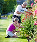 MEADOW FARM  WORCESTERSHIRE: ROBERT AND DIANE COLE DEADHEADING IN THE GARDEN