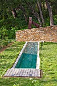DESIGNER: JEAN-LAURENT FELIZIA  FRANCE: LAWN WITH SWIMMING POOL AND WALL WITH WOODLAND BEHIND