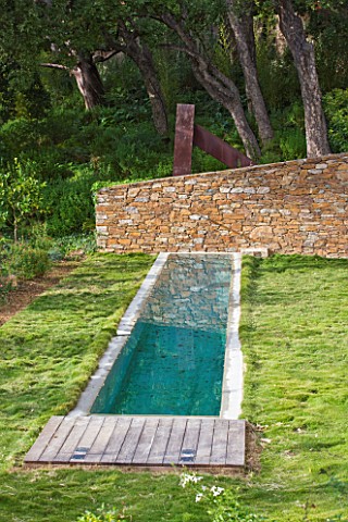 DESIGNER_JEANLAURENT_FELIZIA__FRANCE_LAWN_WITH_SWIMMING_POOL_AND_WALL_WITH_WOODLAND_BEHIND