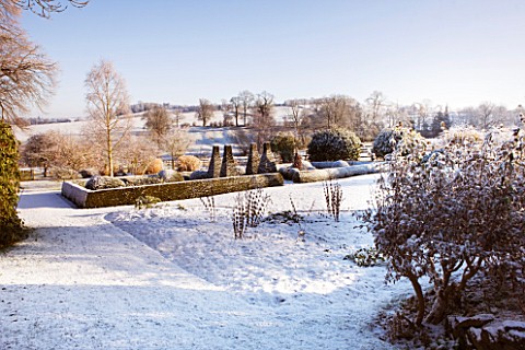 PETTIFERS__OXFORDSHIRE_GARDEN_IN_SNOW_IN_WINTER__VIEW_TOWARDS_THE_PARTERRE_WITH_THE_COUNTRYSIDE_BEYO