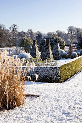 PETTIFERS__OXFORDSHIRE_GARDEN_IN_SNOW_IN_WINTER__VIEW_TOWARDS_THE_PARTERRE_WITH_CLIPPED_TOPIARY_SHAP