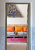 DESIGNERS ERIC OSSART AND ARNAUD MAURIERES  MOROCCO: AL HOSSOUN - VIEW INTO LIVING ROOM WITH ORANGE AND PINK CUSHIONS ON SETTEE