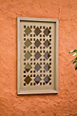DESIGNERS ERIC OSSART AND ARNAUD MAURIERES  MOROCCO: AL HOSSOUN - DECORATIVE WOODEN WINDOW IN ORANGE WALL