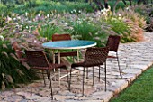 DESIGNERS ERIC OSSART AND ARNAUD MAURIERES  MOROCCO: DAR IGDAD - A PLACE TO SIT - TABLE AND CHAIRS ON PATIO WITH PENNISETUM BORDER