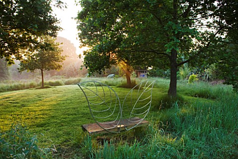 MOORS_MEADOW_GARDEN_AND_NURSERY__HEREFORDSHIRE_THE_WINGED_SEAT_BY_DAVE_BISSELL_AT_DAWN_ON_THE_EDGE_O