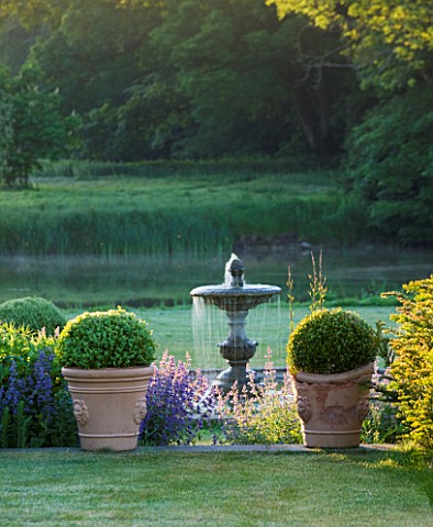 NARBOROUGH_HALL_GARDENS__NORFOLK_DAWN_LIGHT_ON_THE_FOUNTAIN_NEAR_THE_BLUE_GARDEN_WITH_BOX_BALLS_IN_T