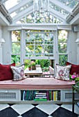 DESIGNER BUTTER WAKEFIELD  LONDON: VIEW OUT OF THE CONSERVATORY WITH WINDOW SEAT CUSHIONS - RED CUSHIONS ARE COTTON VELVET