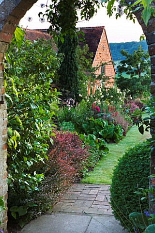 SANDHILL_FARM_HOUSE__HAMPSHIRE__DESIGNER_ROSEMARY_ALEXANDER_VIEW_THROUGH_ARCH_TO_RED_BORDER_WITH_ROS