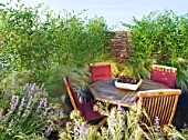 LONDON ROOFTOP GARDEN: WOODEN TABLE AND CHAIRS ON WOODEN DECKING SURROUNDED BY STIPA TENUISSIMA AND PHYLOSTACHYS AUREA