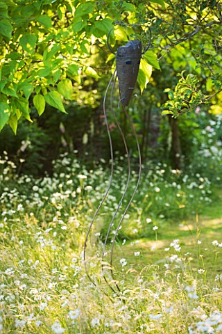 DESIGNER_ALISON_HENRY__PRIVATE_GARDEN_COTSWOLDS_MEADOW_WITH_OXE_EYE_DAISIES_AND_METAL_MASK_WIND_SCUL