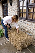 DESIGNER CLARE MATTHEWS - GROWING STRAWBERRIES AND NASTURTIUMS IN A STRAW BALE: USE A BREAD KNIFE TO CREATE A HOLE FOR PLANTING