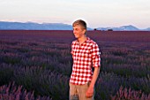 TEENAGE BOY (AGED 16) WITH RED AND WHITE SHIRT IN FIELD OF PURPLE LAVENDER NEAR VALENSOLE  PROVENCE  FRANCE. SUMMER  JULY