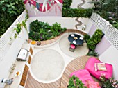 SMALL TOWN GARDEN  LONDON. DESIGNER - ANA SANCHEZ - MARTIN  OF GERMINATE DESIGN. VIEW LOOKING DOWN ONTO PINK AND WHITE GARDEN WITH DECKING  PINK CHAIRS  MOSAIC BY CELIA GREGORY