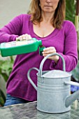 DESIGNER CLARE MATTHEWS: CLARE PUTTING LIQUID FEED INTO A WATERING CAN